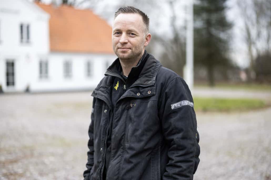 Snedkermesteren foran hvid hovedbygning på godset