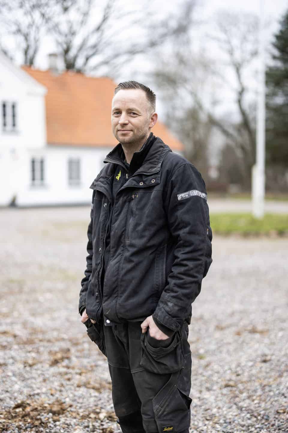 Snedkermesteren foran hvid hovedbygning på godset